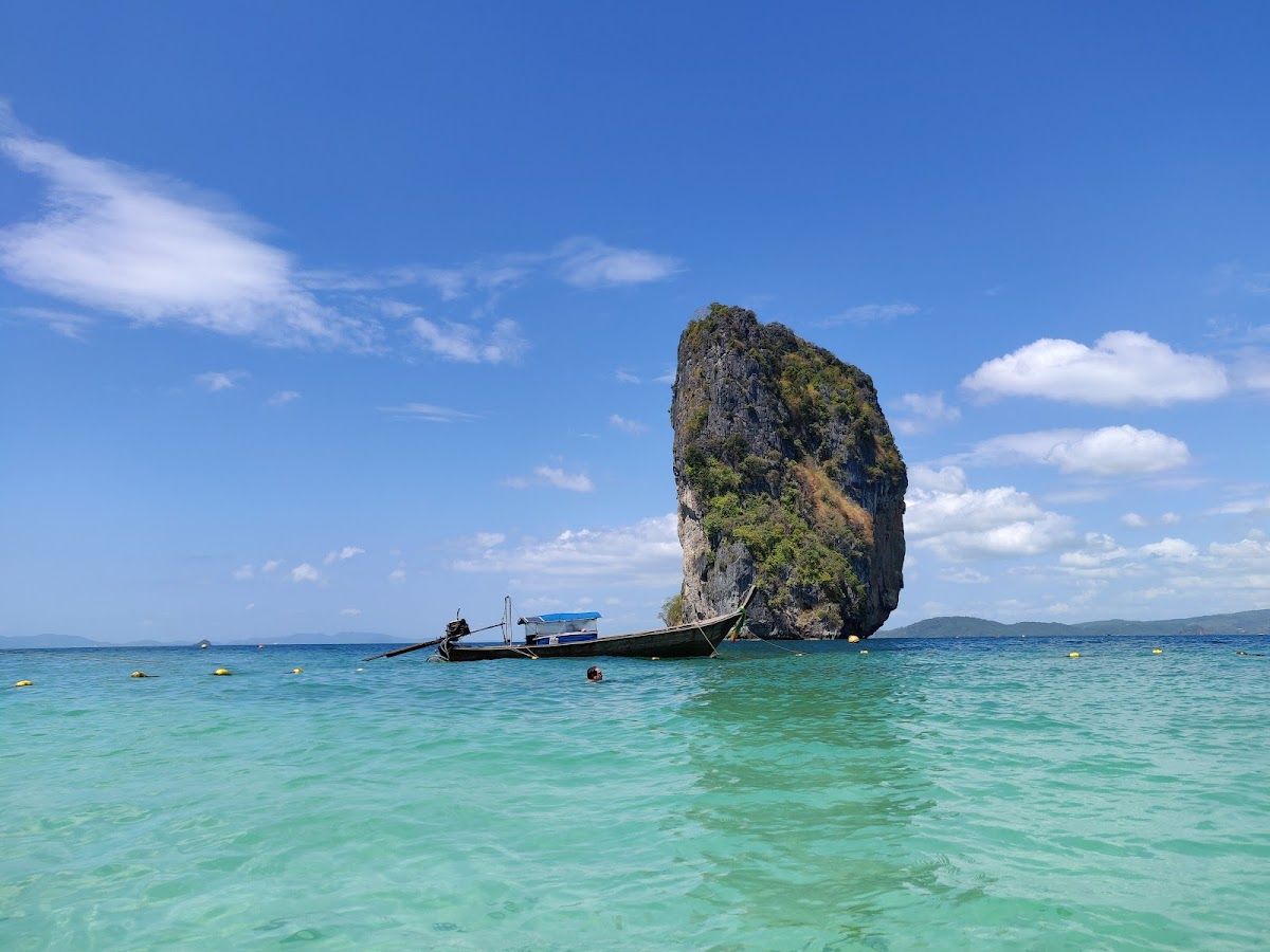 Ko Poda island near Krabi, a tall karst rock rising from clear turquoise water with a longtail boat moored beside it