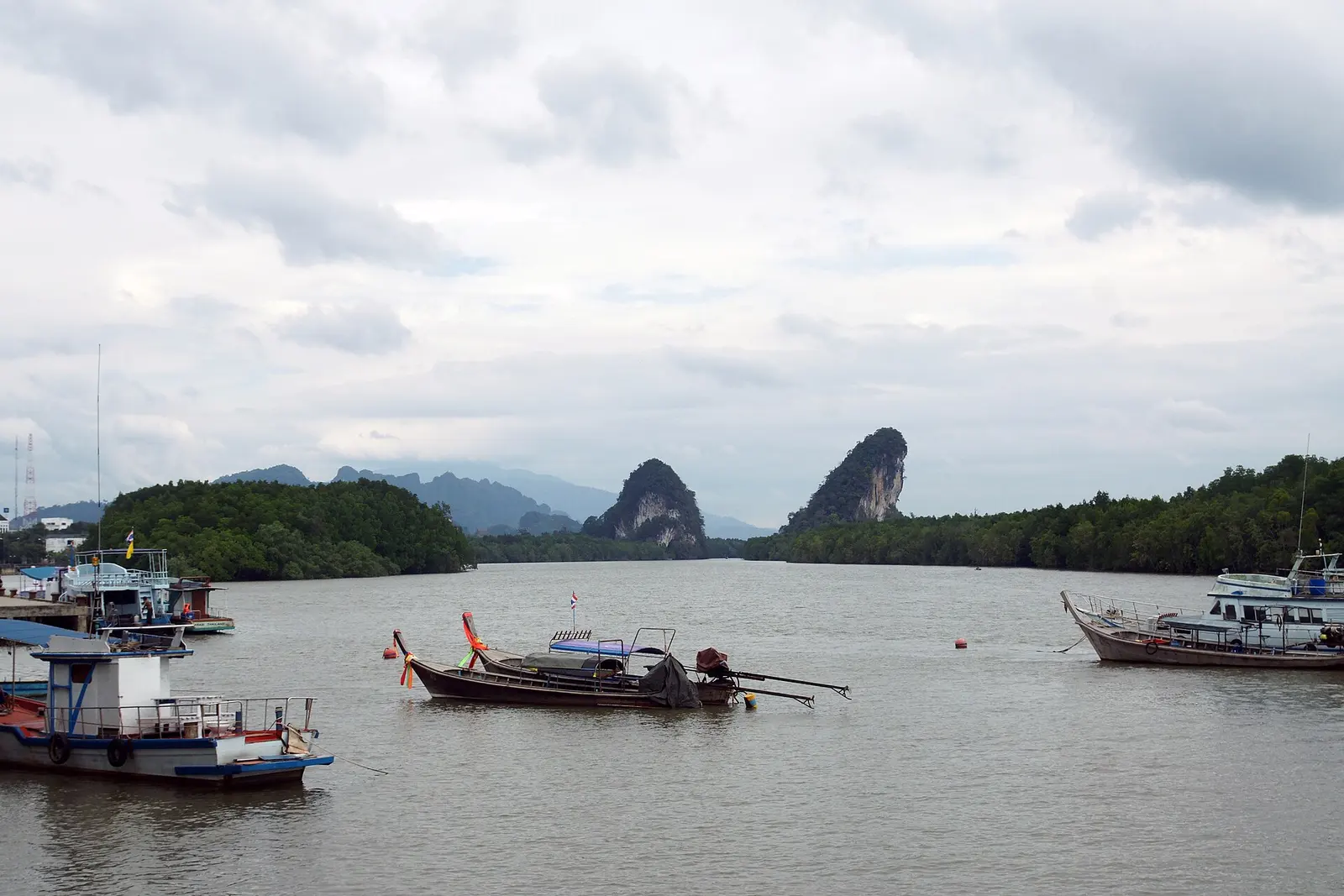 Krabi Town riverside, with the white clock tower and mangrove hills behind the roofs