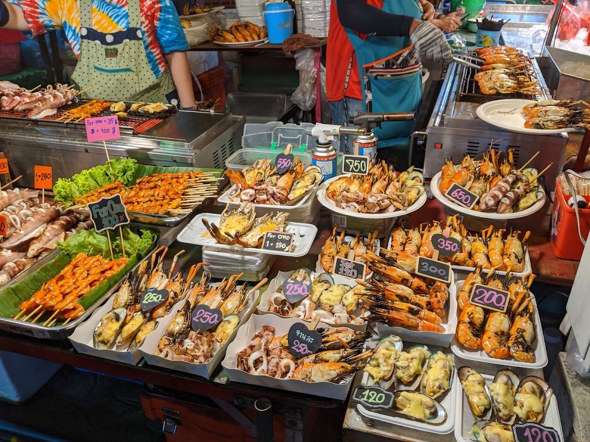 A night-market seafood stall in Krabi with plates of grilled prawns, squid and skewers laid out with prices