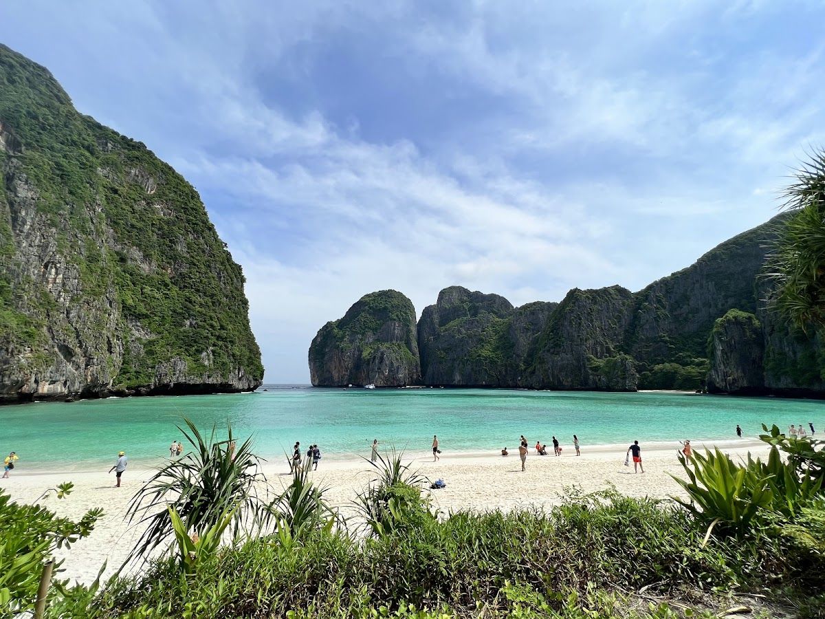 Maya Bay on Phi Phi Leh, a curved white-sand beach ringed by tall green cliffs and turquoise water with visitors on the sand