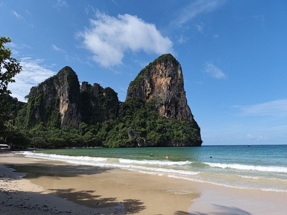 Railay West Beach in Krabi with twin limestone towers rising above the sand and shallow surf