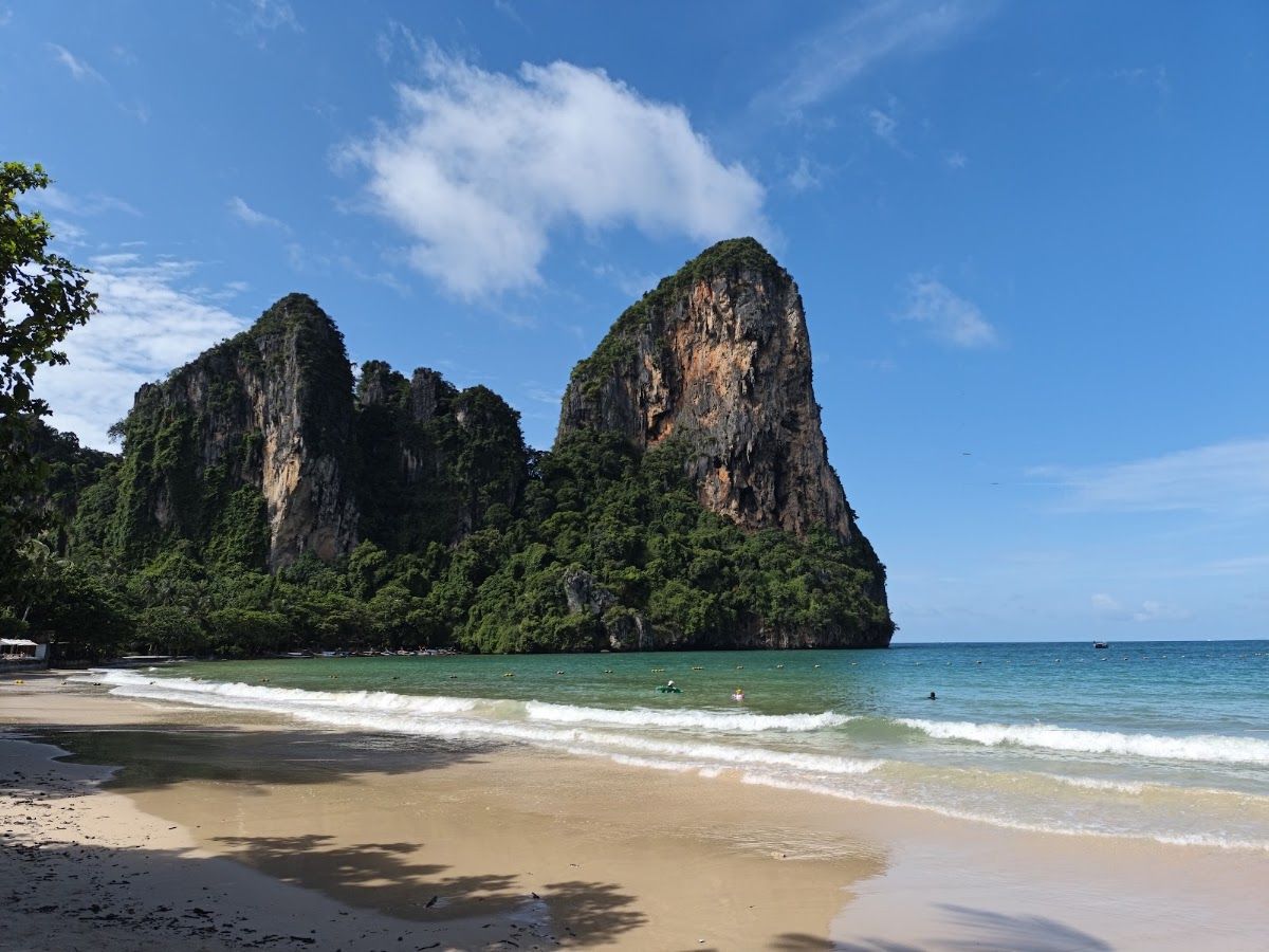 Railay West Beach in Krabi with twin limestone cliffs rising above the sand and clear turquoise water
