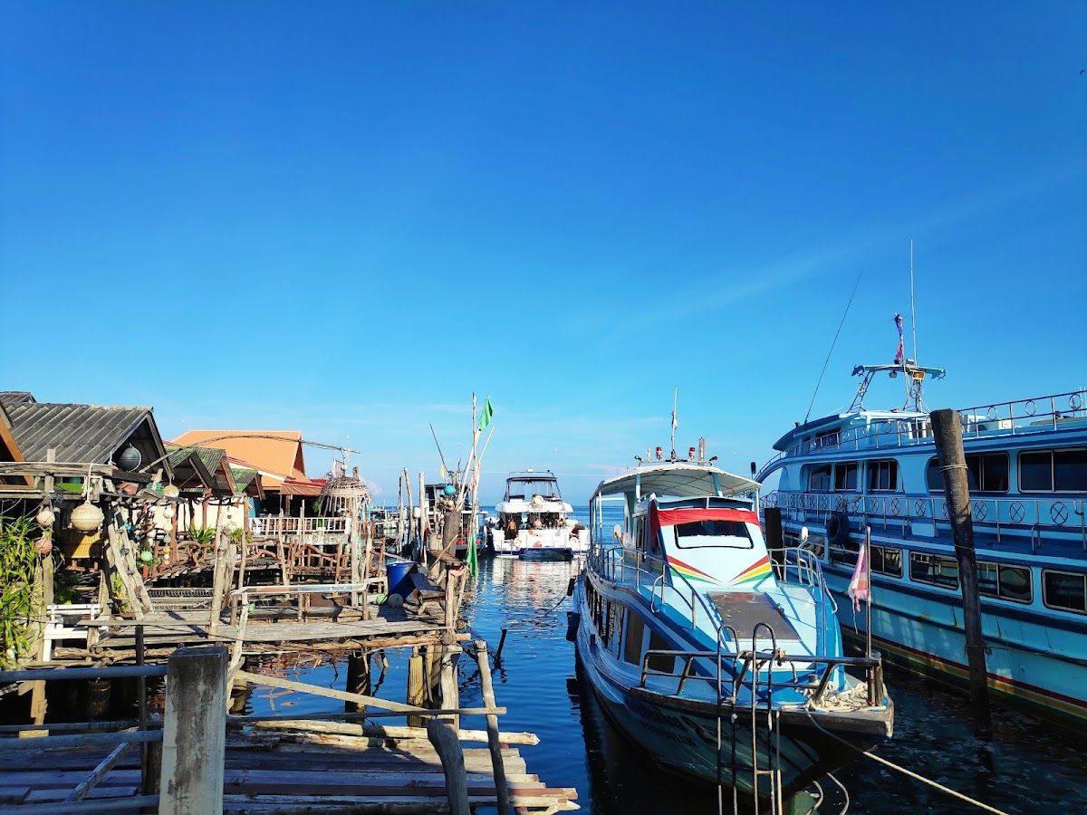 Passenger ferry boats moored at Saladan Pier on Koh Lanta, with clear blue sky and wooden jetty