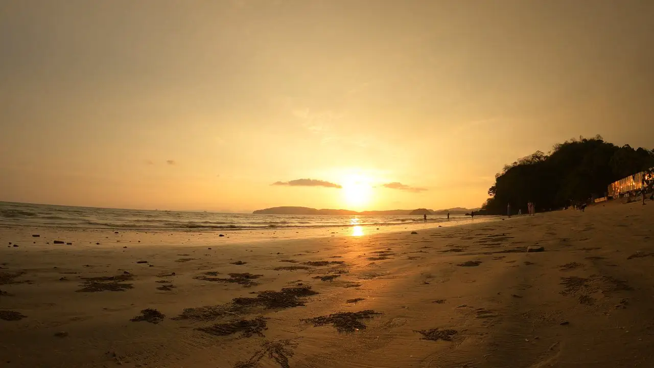 Ao Nang beach at sunset, longtail boats on the sand and limestone islands across the bay